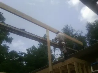 Carpenter setting a ridge beam over a new addition frame — Ice Dam Removal by Roofing Brothers in Goodell
