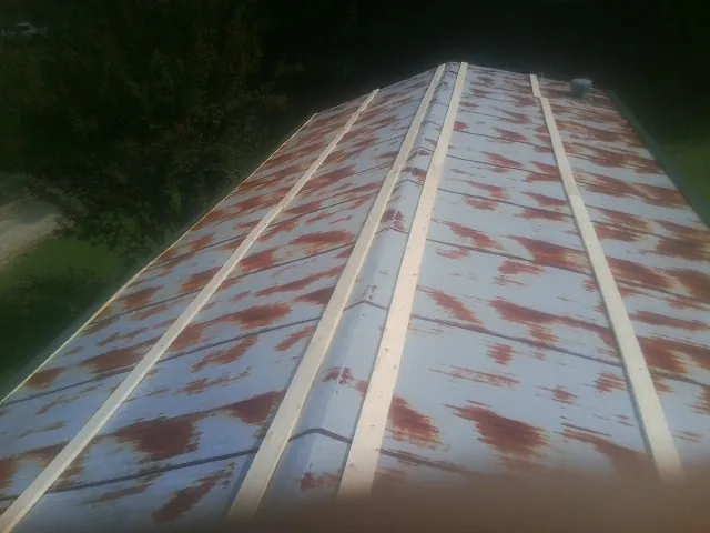 Rusted metal roof panels with new wood purlins before replacement — Storm Damage Roof Repair in Goodell by Roofing Brothers
