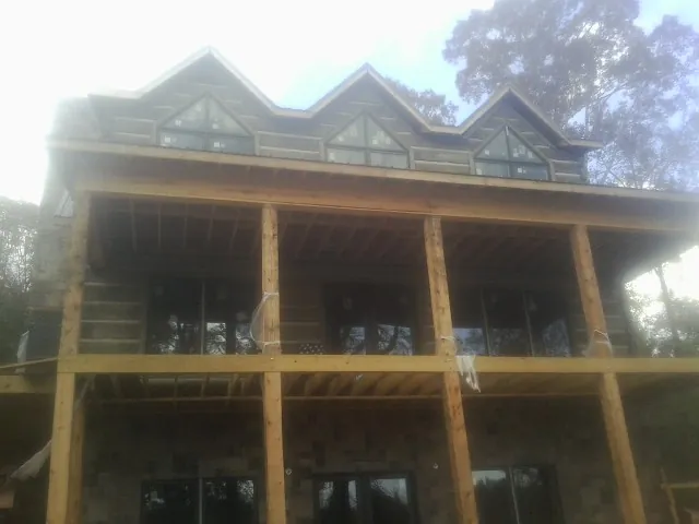 Dormers and porch framing on a large log home under construction — Roof Coating work by our crew in Goodell