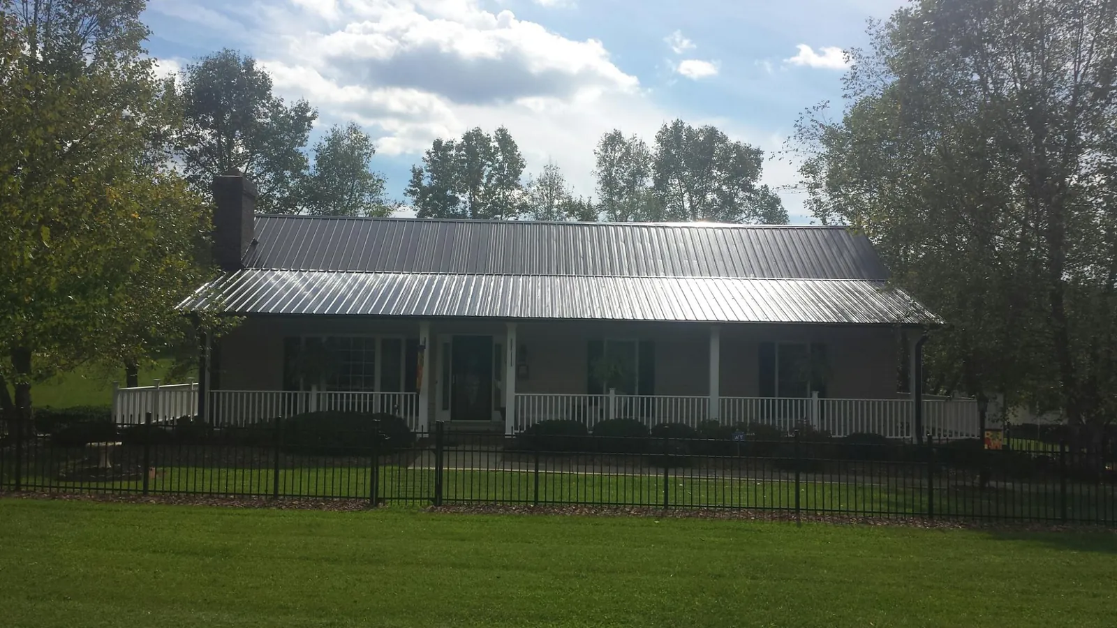 Gray metal roof on a brick ranch with a full width front porch — Gutter Guard Installation work by our crew in Goodell