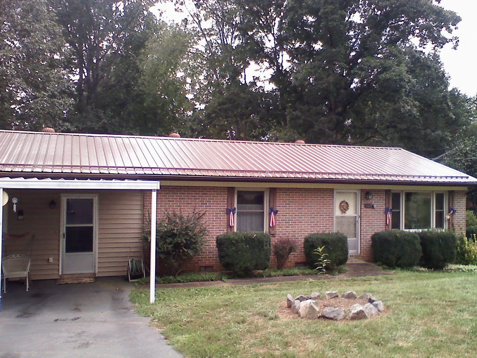 Bronze metal roof and carport on a brick ranch home — Roof Repair work by our crew in Goodell